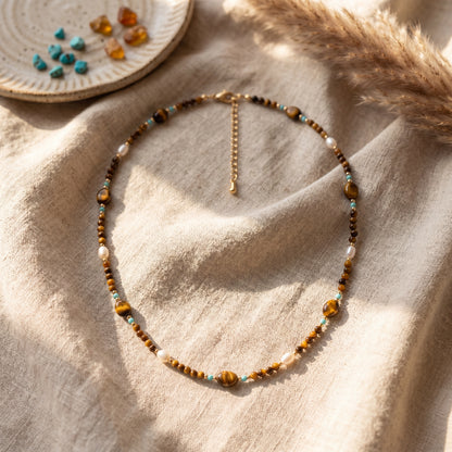 Tierra necklace with natural tiger's eye, turquoise, and natural baroque pearls styled with pampas grass in warm light.