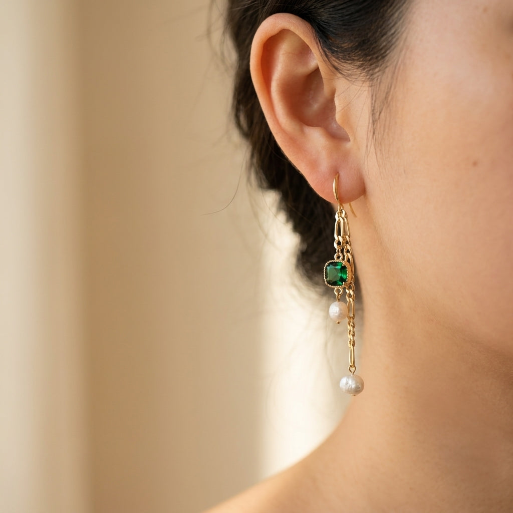 Side view of a model wearing the “Verdant Muse” Emerald and Freshwater Baroque Pearl Drop Earrings in 14K gold