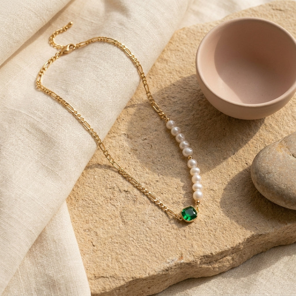 Natural sunlight highlighting the Verdant Muse emerald pendant and freshwater pearls on a warm stone background