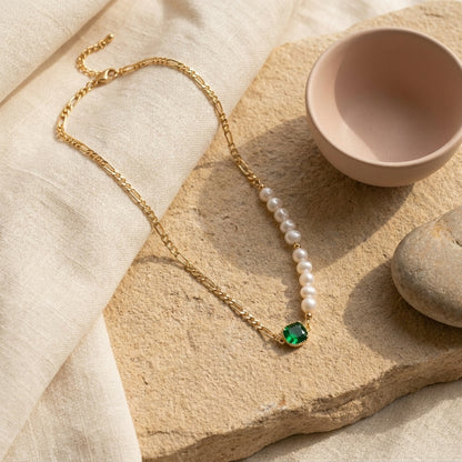 Natural sunlight highlighting the Verdant Muse emerald pendant and freshwater pearls on a warm stone background