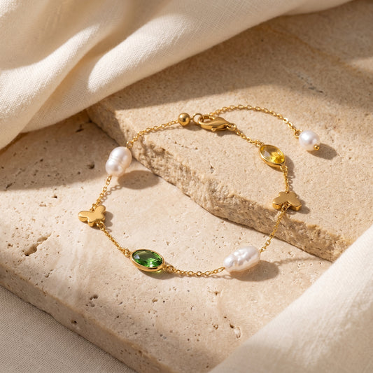 18K gold-plated Papillon baroque pearl and green zircon butterfly bracelet displayed on a textured stone surface by Whisperland Studio.